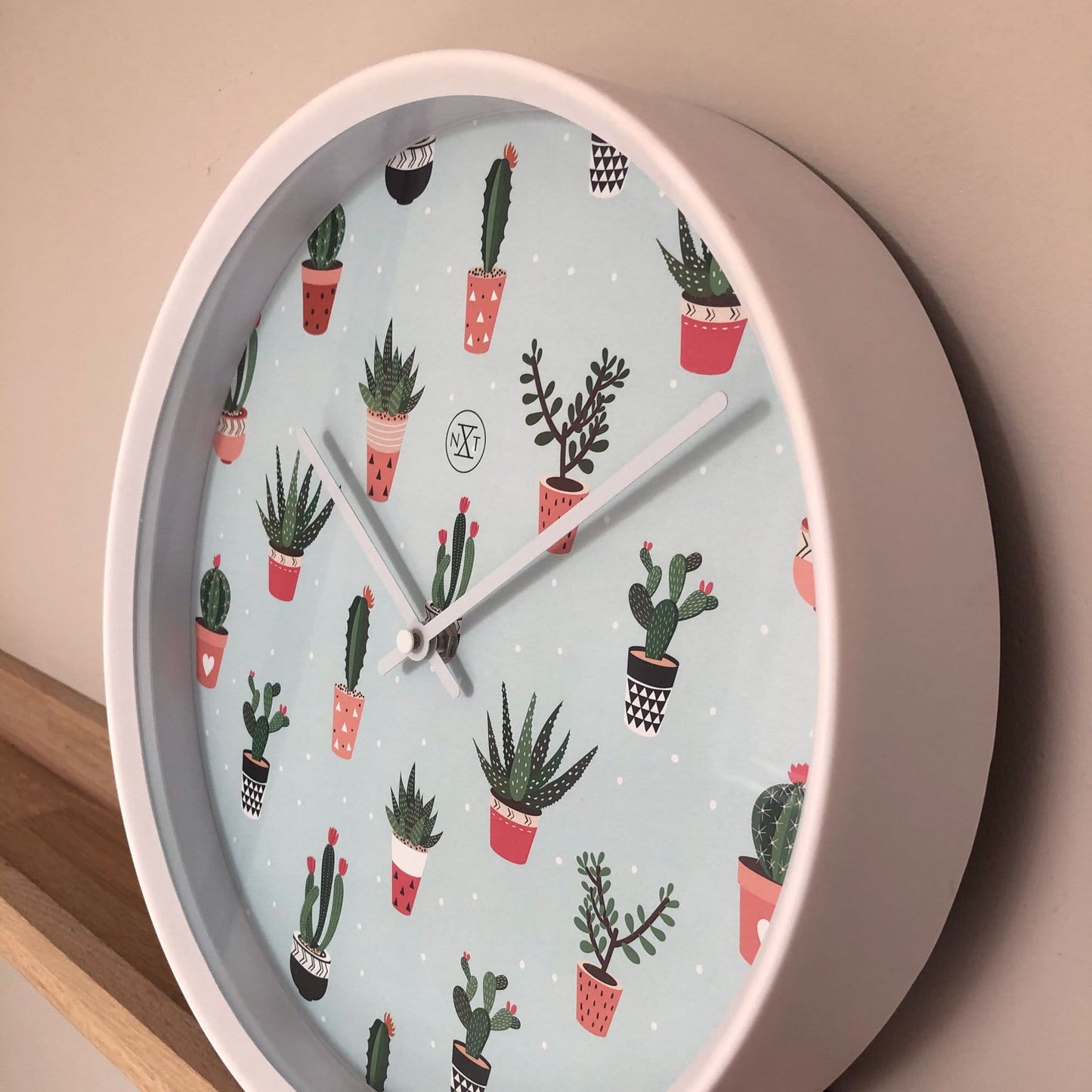Plastic wall clock featuring a 30 cm cactus design by NeXtime Clocks, with a round shape and desert-inspired motif.